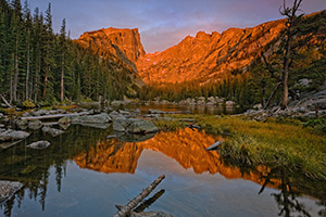 Still and peaceful, Dream Lake in Rocky Mountain National Park reflects an image of the majestic Hallett Peak while it glows red with the light of the rising sun. - Colorado Photograph