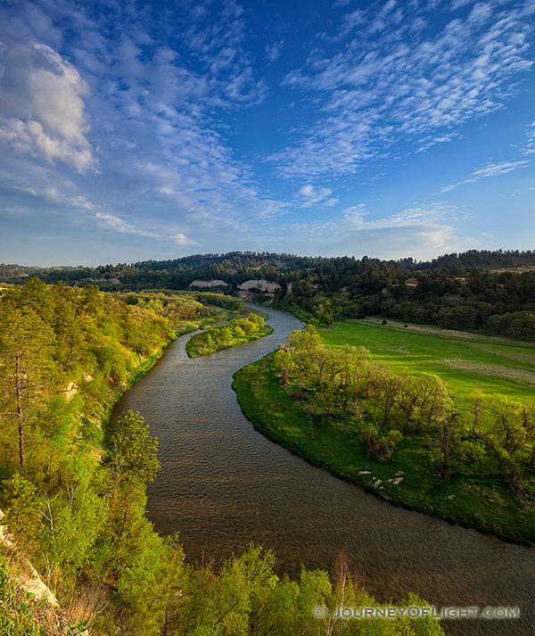 The Niobrara river, snakes through a lush green valley on a beautiful spring morning. A cool breeze blew gently as the sun rose in the east illuminating the clouds in the sky. - Valentine Photography