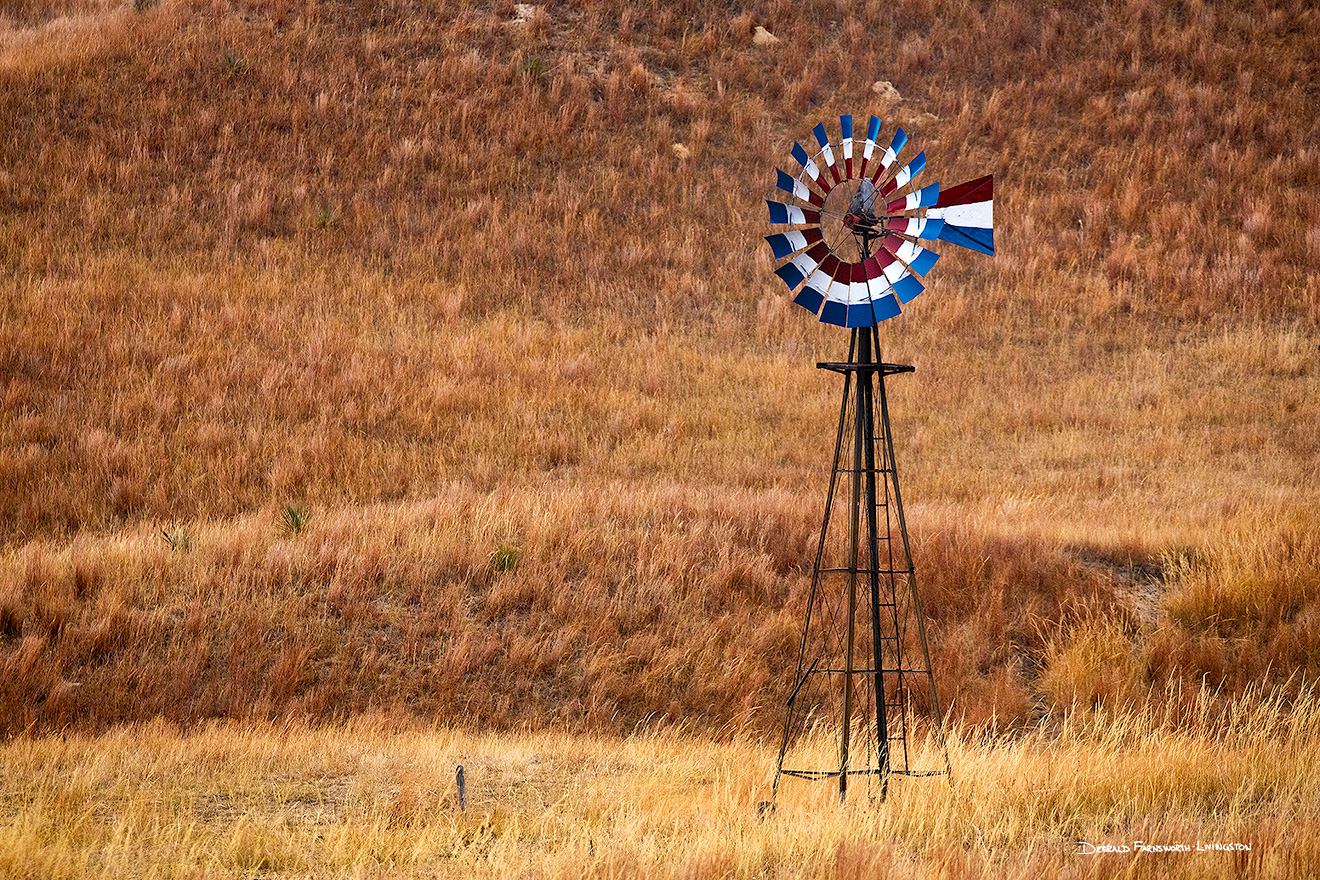 A scenic landscape photograph of a windmill painted red, white, and blue in the sandhills of Nebraska. - Nebraska Picture