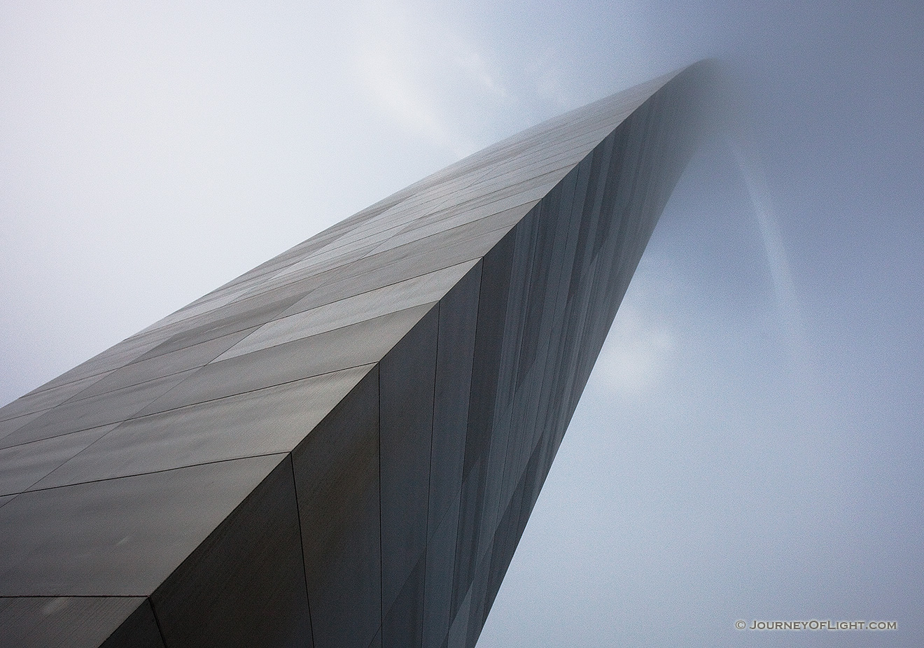 From the base of the north leg looking in a south easterly directly, the Gateway Arch curves through the sky and into the fog.  - Jefferson National Expansion Memorial Picture