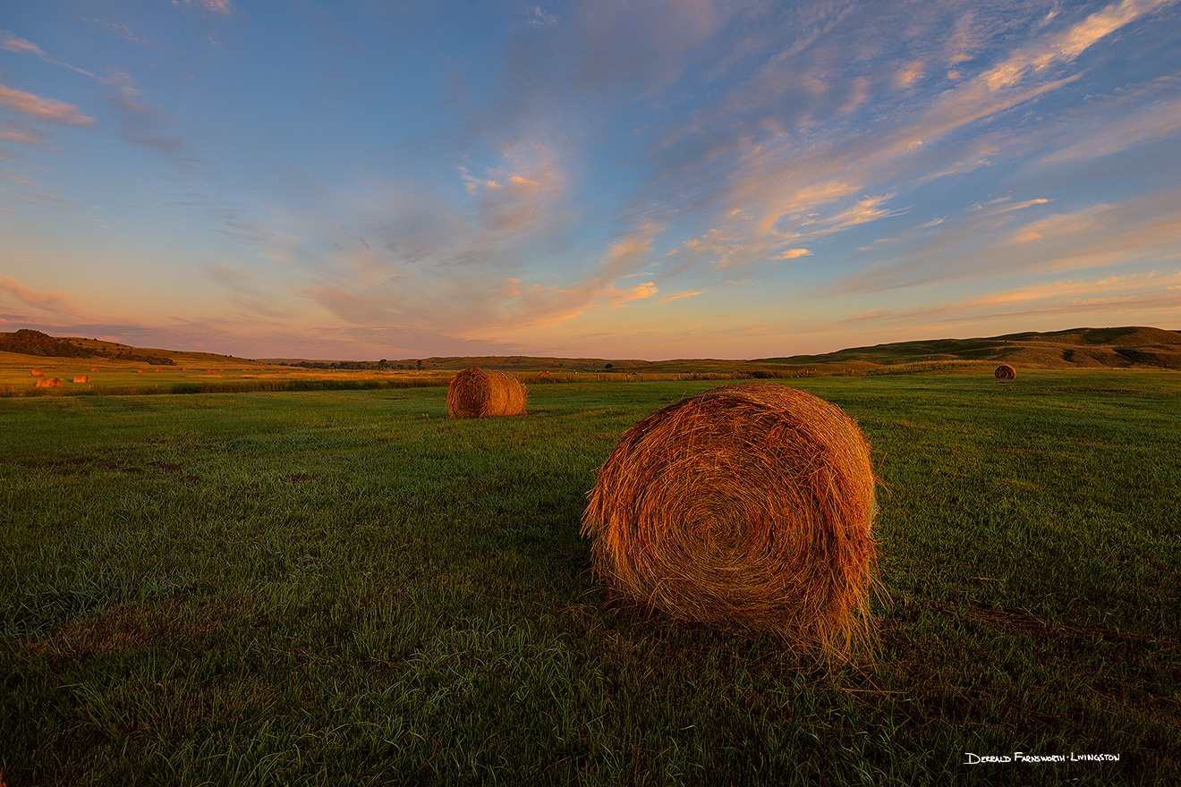 A scenic landscape photograph of hay bales and a beautiful glow in the sandhills of Nebraska. - Nebraska Picture