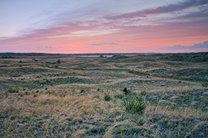 As the sun sets, the clouds ablaze with red hues over the undulating hills of central Nebraska. - Nebraska Photograph