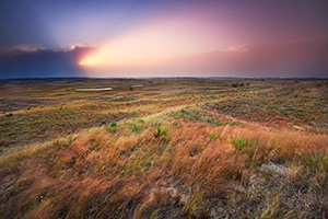 The intense light of the setting sun streams out of clouds in the distance across the sandhills at Valentine National Wildlife Refuge, Nebraska. - Nebraska Photograph