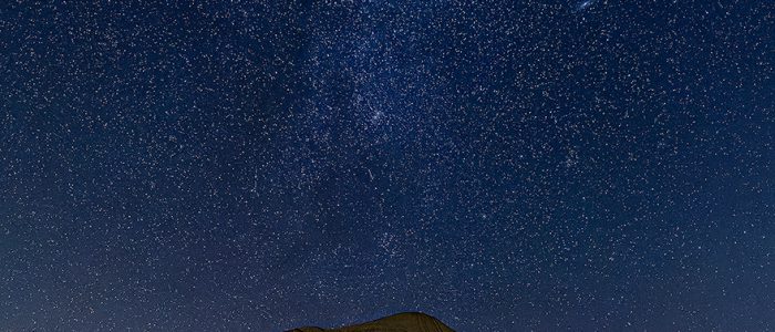 The badlands of Toadstool Geologic Park are illuminated by a single flashlight while the stars above shine brightly.